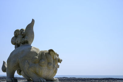 Close-up of statue against sea and clear sky