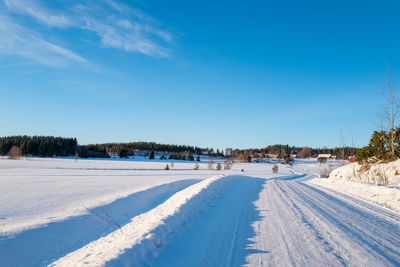 Snow covered field against blue sky