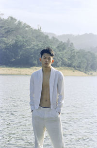 Portrait of young man standing against sea