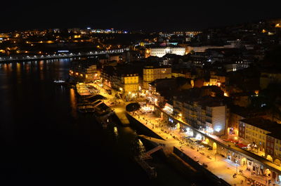 High angle view of illuminated city by buildings at night