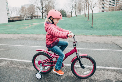 Side view full length of girl riding bicycle on walkway