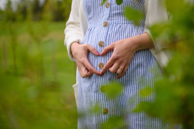 Midsection of woman holding umbrella standing on field