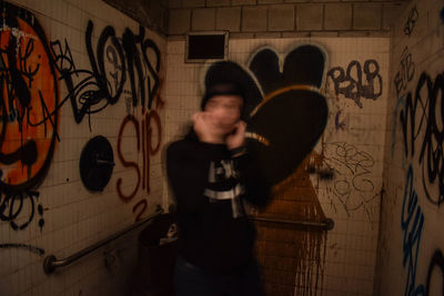 Side view of man standing against graffiti wall