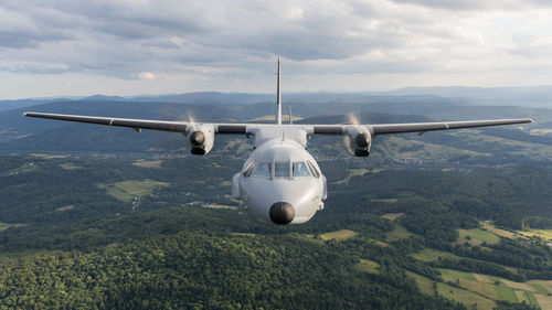 Airplane flying over landscape against sky