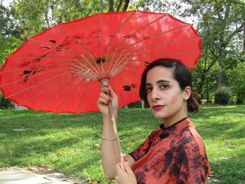 Portrait of young woman holding umbrella during rainy season