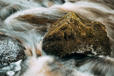 Close-up of water flowing on rock against sky