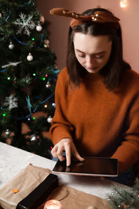 A young woman holds a phone, a tablet in her hand  the concept of preparing for the new year
