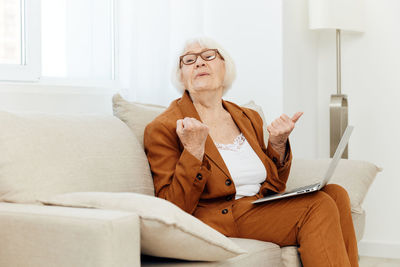 Portrait of young woman sitting on sofa at home