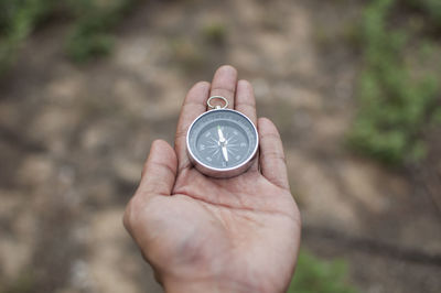 Close-up of woman holding navigational compass on field