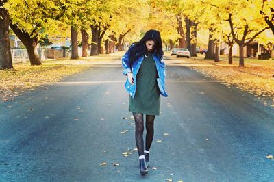 Full length of young woman walking on road during autumn