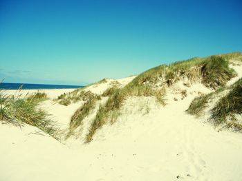 Scenic view of beach against clear blue sky