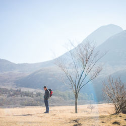 Side view of woman standing on field against mountain