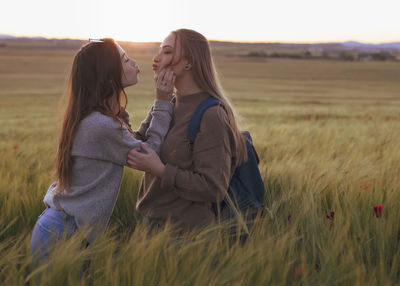 Two women holding hands at sunset in the field