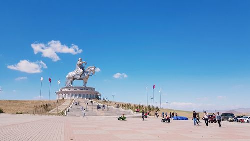 Group of people at statue against blue sky