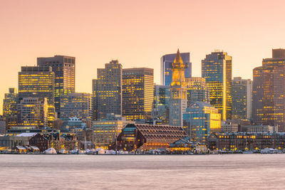 Modern buildings in city against clear sky during sunset