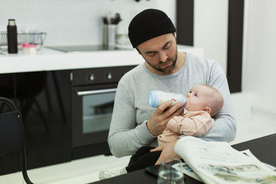 Father holding baby while sitting at home