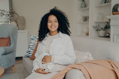 Smiling pregnant woman looking away sitting in sofa