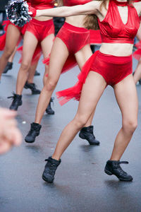 Low section of cheerleaders dancing on footpath