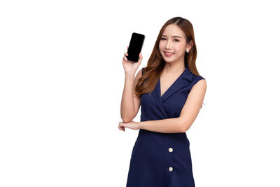 Young woman using phone while standing against white background