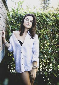 Beautiful young woman standing against plants