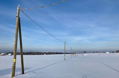 Poles on snow covered landscape against sky
