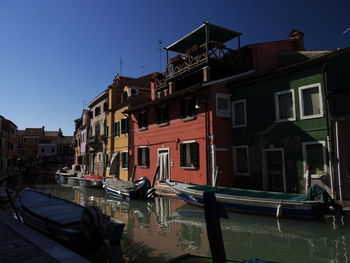 Boats moored in canal by buildings against sky in city