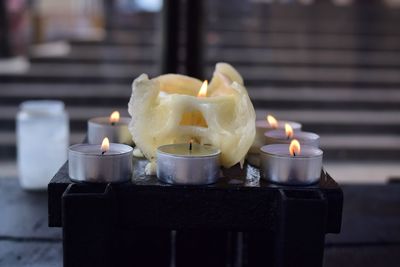 Close-up of lit candles on table in illuminated building