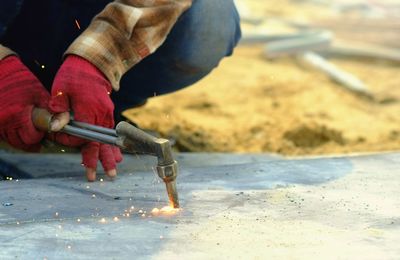 Cropped hands of manual worker welding metal at construction site