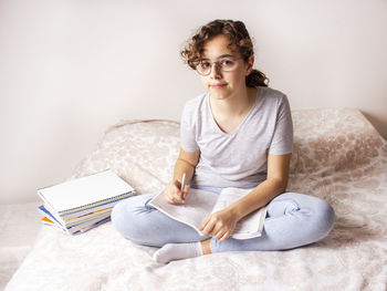 Young woman sitting on book at home