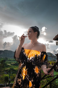 Young woman looking away against sky