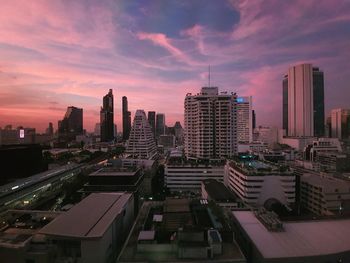 Modern buildings in city against sky during sunset