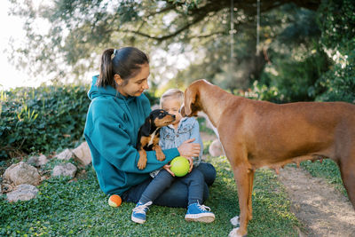 Side view of boy playing with dog on field