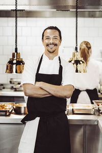 Porträtt av glad manlig kock i restaurangkök
