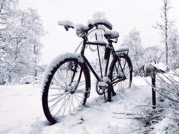 Bicycle on snow field against sky