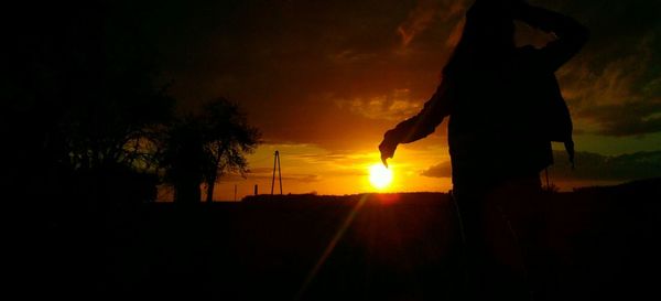 Silhouette people on field against sky during sunset