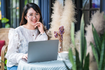 Portrait of smiling young woman using mobile phone outdoors