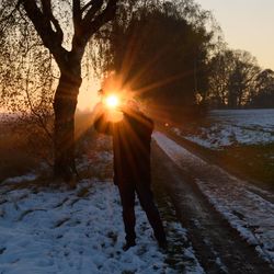 Man walking on snow covered tree during sunset