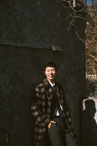 Portrait of young man standing against wall