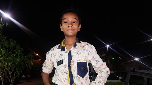 Portrait of smiling boy standing against sky at night