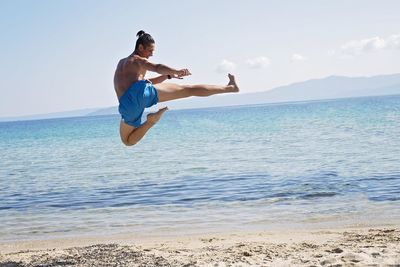 Full length of man jumping on sea against clear sky