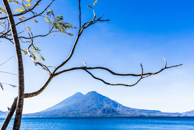 Scenic view of sea and mountains against blue sky