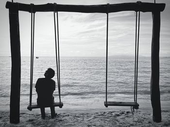 Rear view of man standing by sea against sky