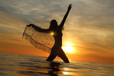 Silhouette person on beach against sky during sunset