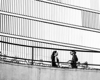 Side view of man and woman sitting on railing