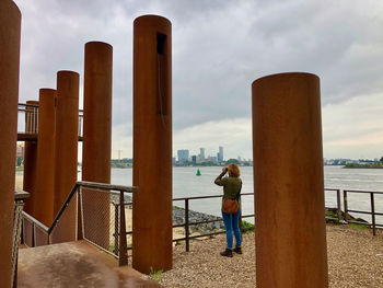 Rear view of people standing by railing against sea