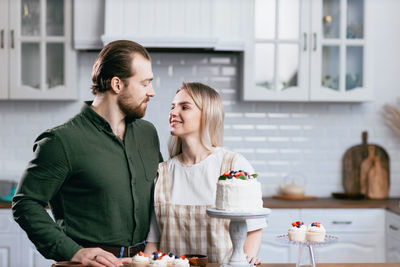 Couple embracing by cake in kitchen