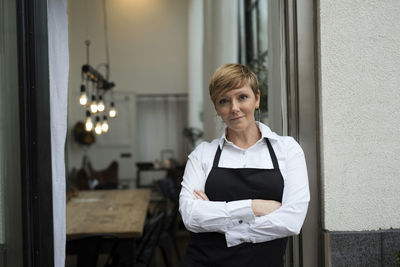 Confident business professional standing with arms crossed against workshop