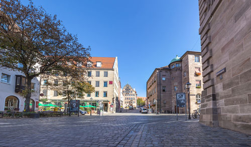 Street amidst buildings against blue sky