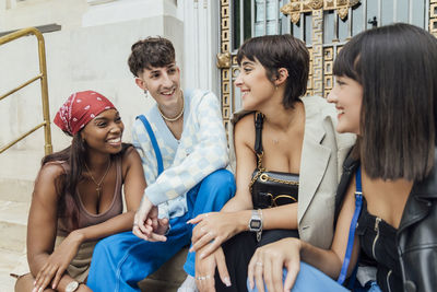 Happy friends talking with each other on staircase in front of door