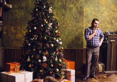 Portrait of mid adult man standing by christmas tree at home